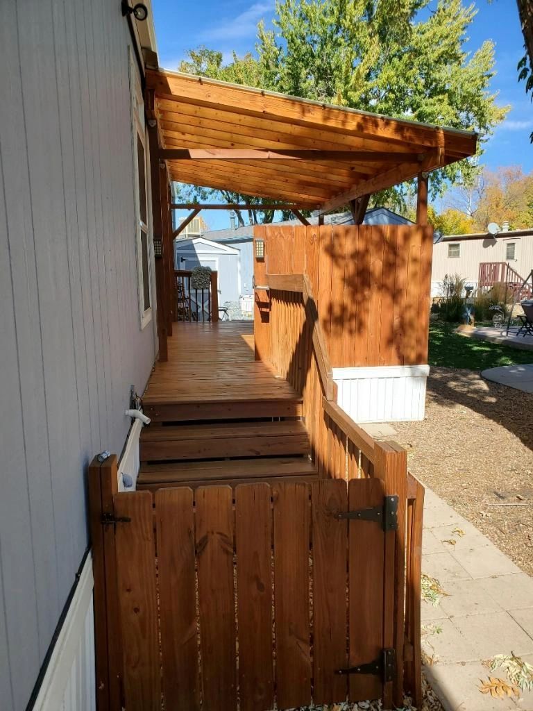Stained wood walkway, steps, and overhead cover along a house
