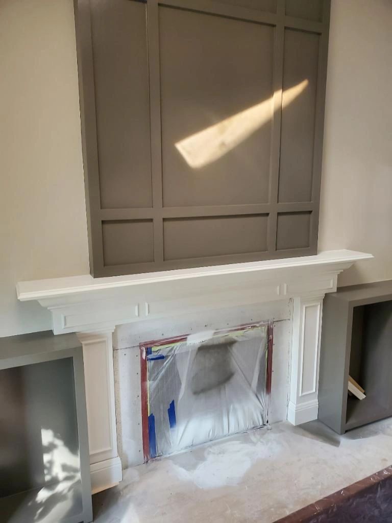 Fireplace surround with a taupe paneled grid; plastic still on the hearth