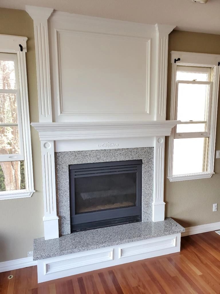 White painted fireplace mantel and paneling between two windows