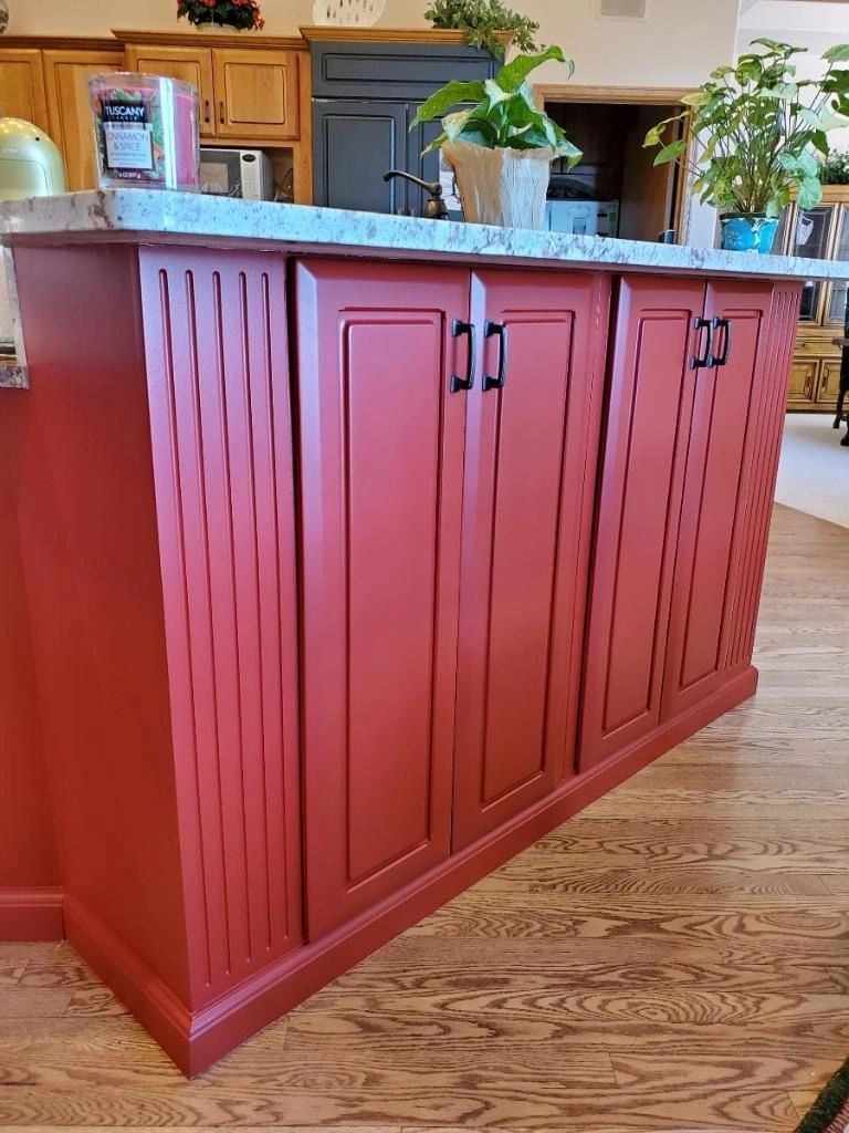 Kitchen island with cinnamon-red cabinet doors and black pulls