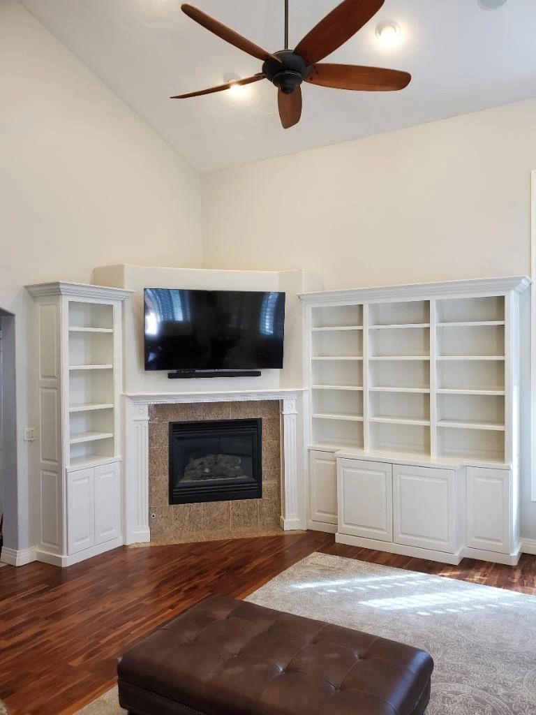 White built-in shelves flanking a stone fireplace in a vaulted living room — a Latham Painting job photo