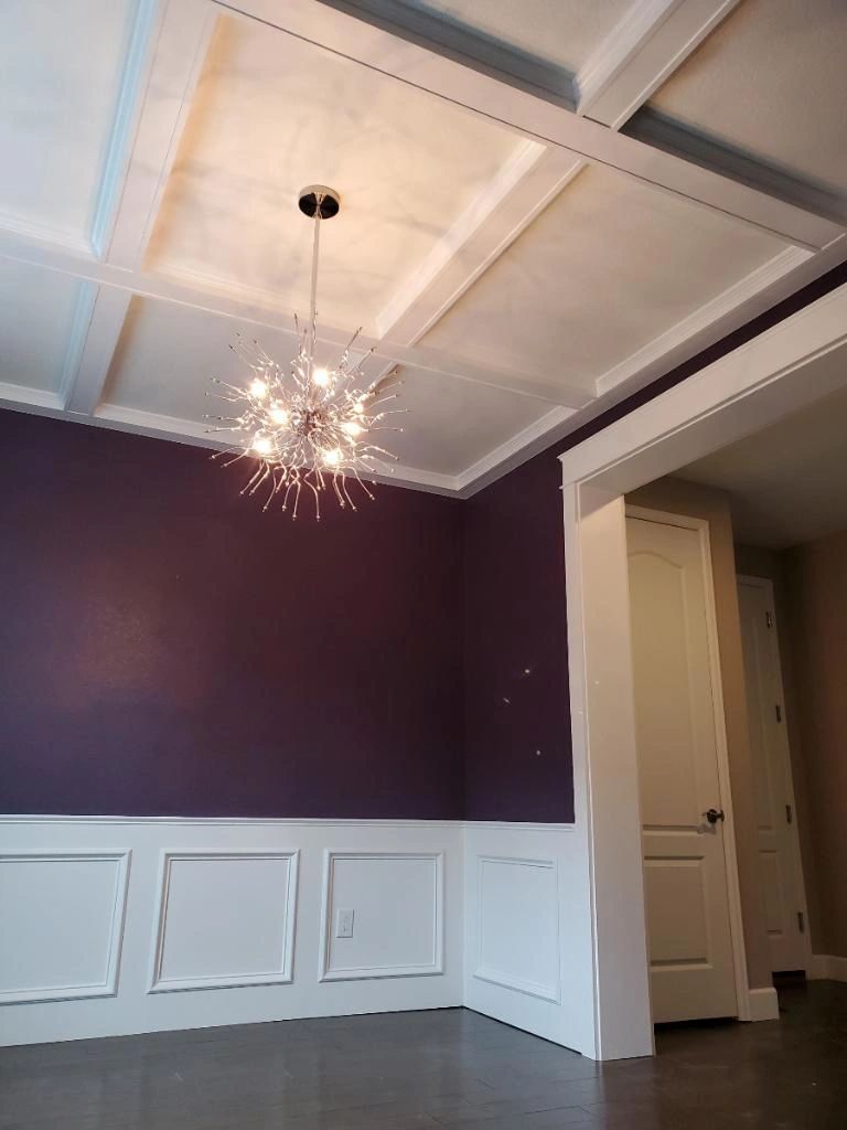 Deep purple wall above white wainscoting and a coffered ceiling