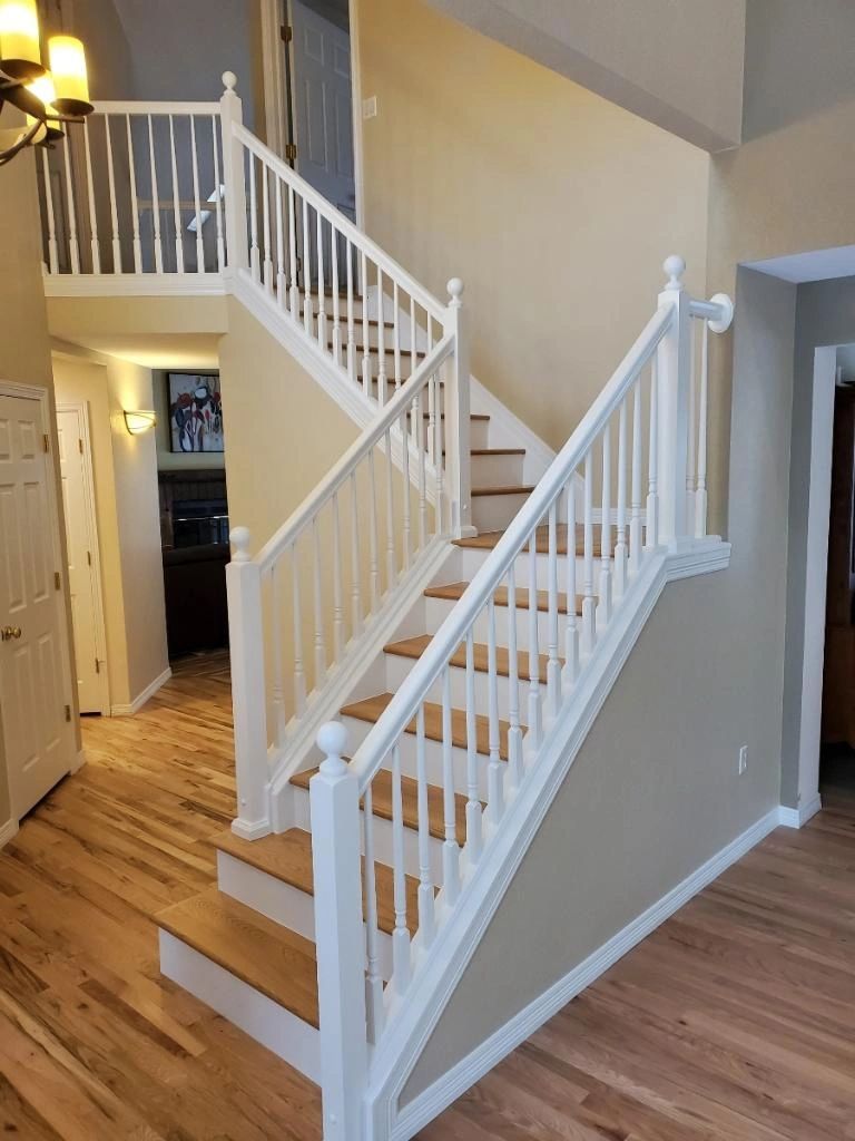 Two-story stair with tan walls and crisp white rail and trim